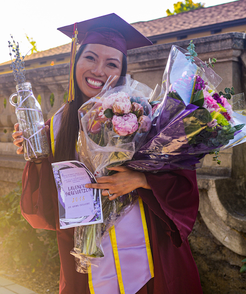 young woman in grad cap and gown with flowers
